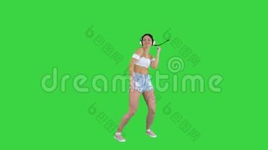高加索女<strong>模特</strong>戴着<strong>耳机</strong>跳跃，在绿色屏幕上表达快乐的情绪，Chroma键